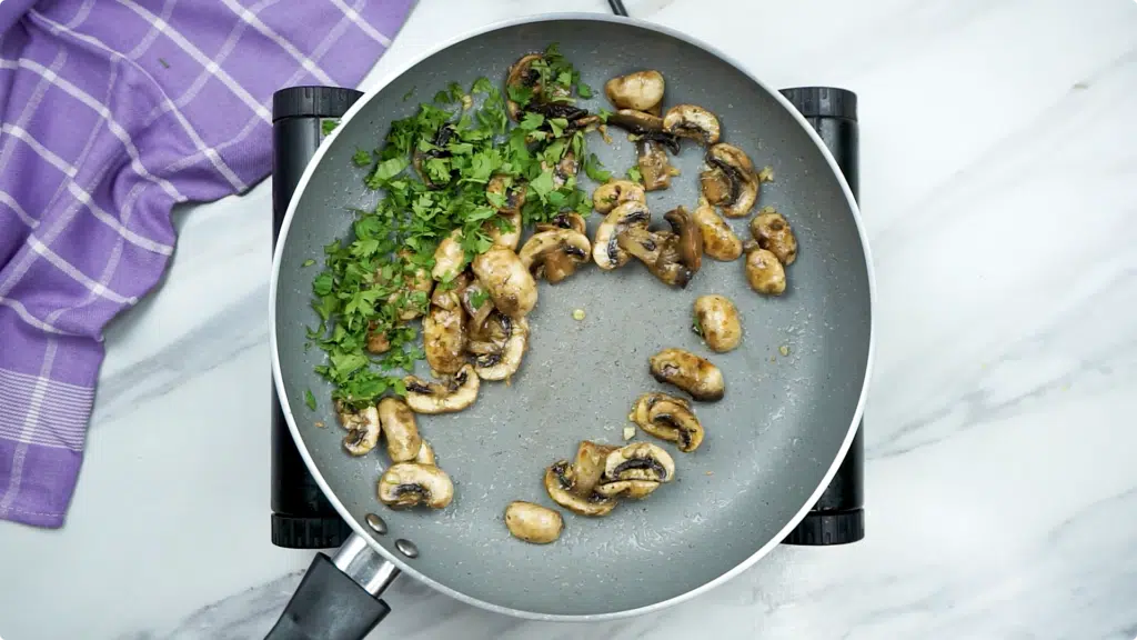 Steamed mushrooms in a pan with garlic and fresh parsley