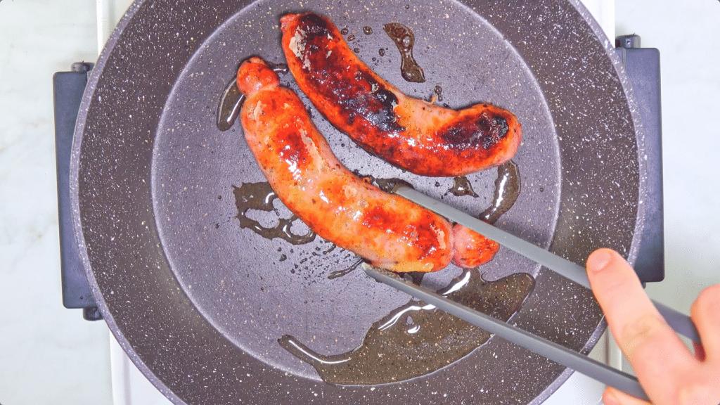 Sausages being refried in a pan