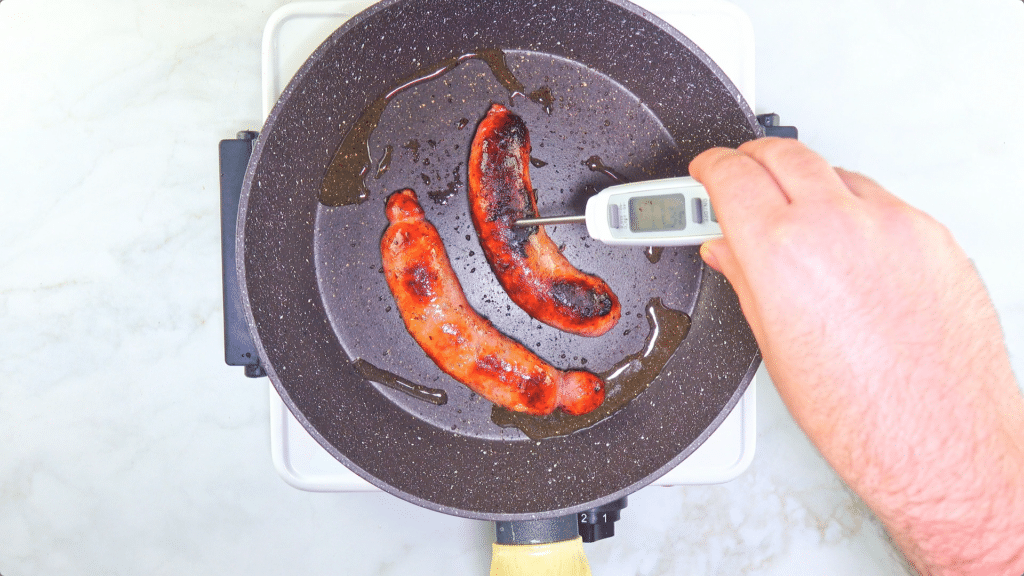 Checking temp of sausages in a pan