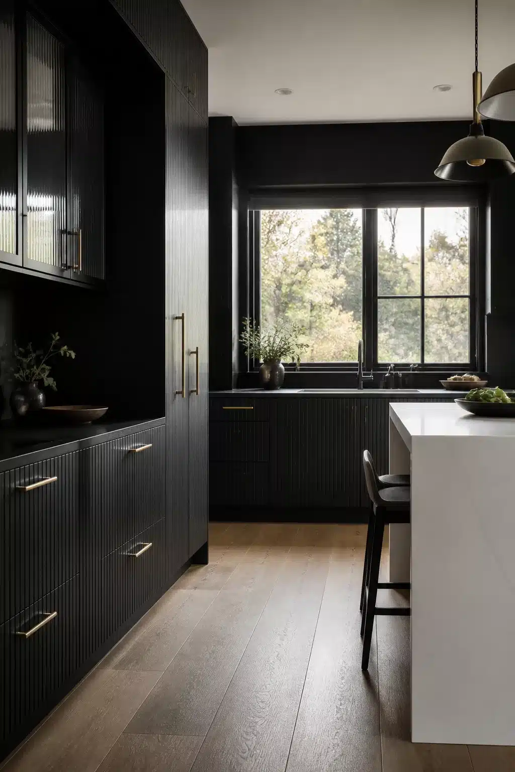 Black kitchen aesthetic ideas with fluted cabinet doors, brushed brass pulls, white island, and warm wood floors