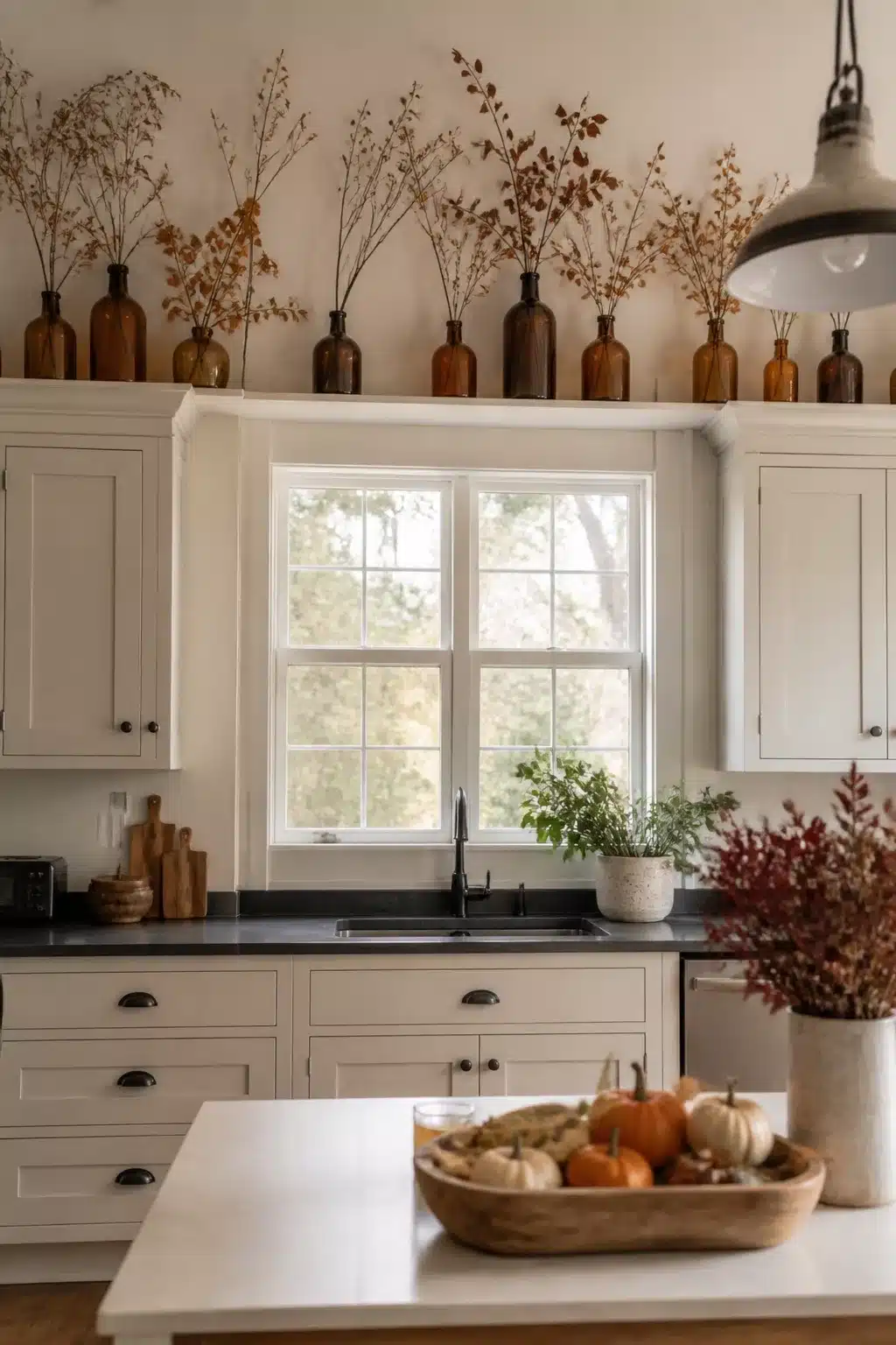 Amber glass bottles with dried branches on white kitchen cabinets — fall kitchen cabinet decor idea