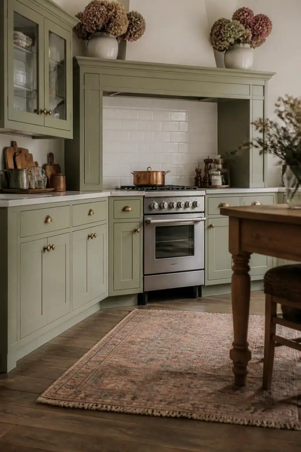 Fall kitchen cabinet decor with dried hydrangeas in white crocks atop sage green shaker cabinets with brass hardware.