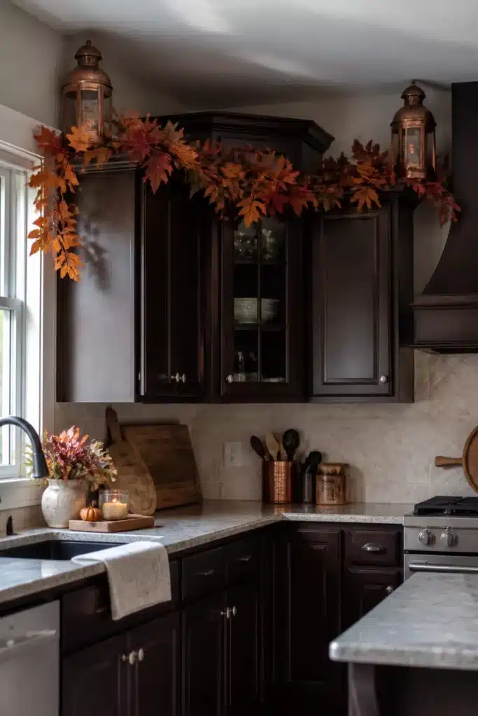 Fall kitchen cabinet decor with copper lanterns and a full maple leaf garland above dark espresso cabinets.