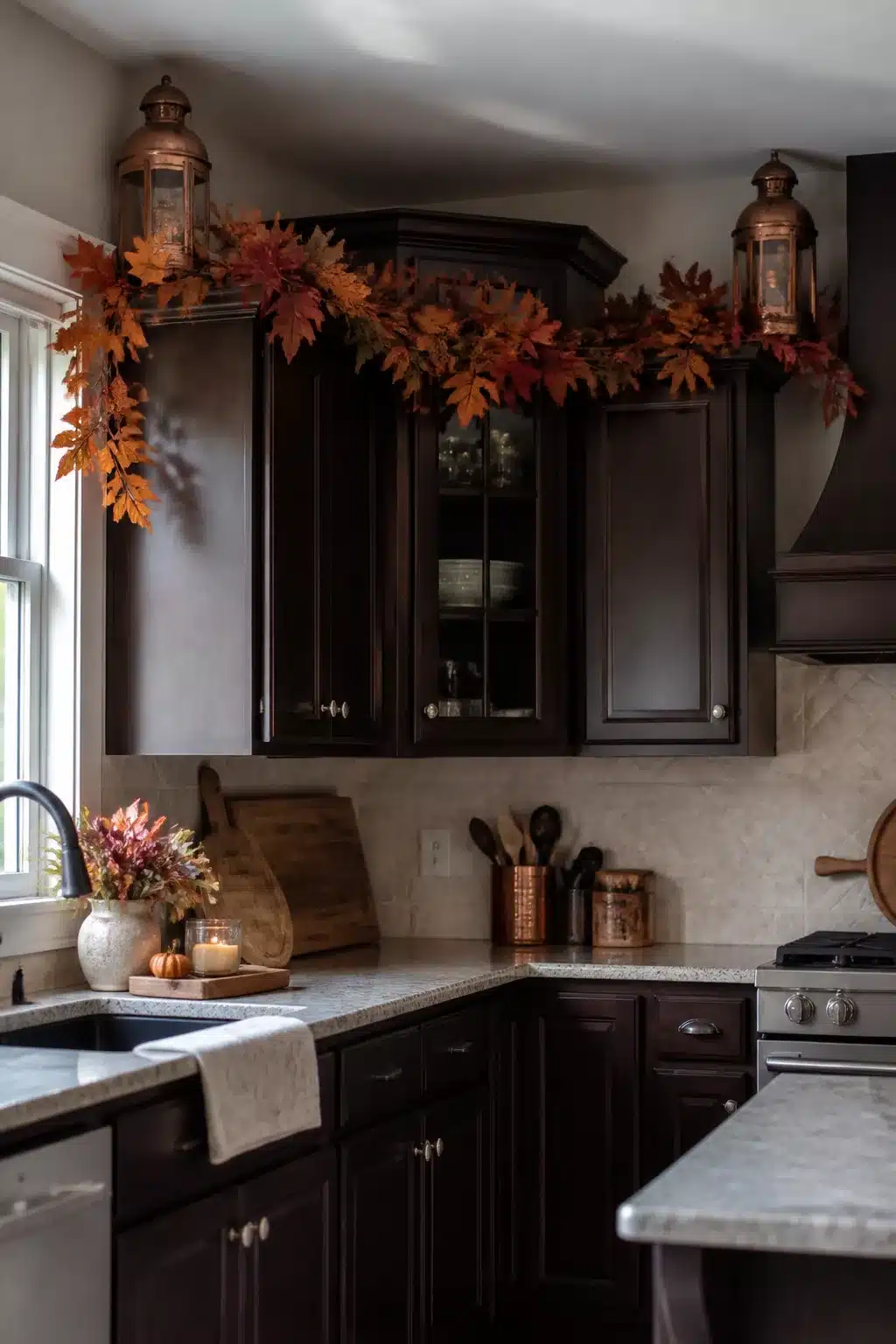 Fall kitchen cabinet decor with copper lanterns and a full maple leaf garland above dark espresso cabinets.