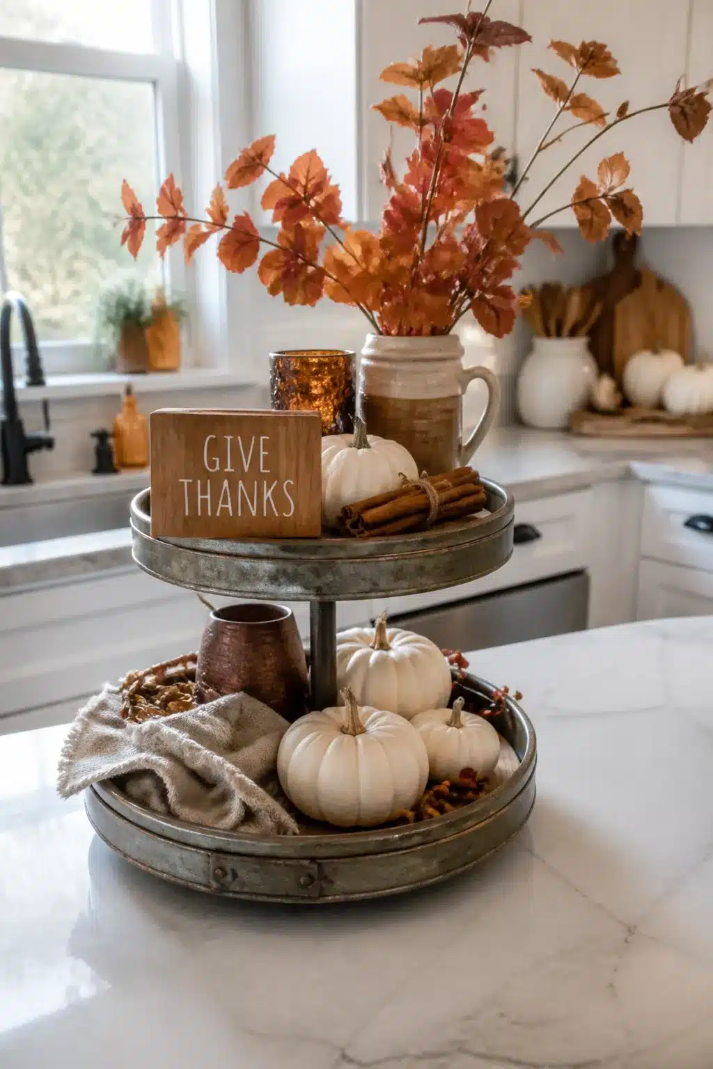 Fall kitchen decor with a galvanized tiered tray styled with white mini pumpkins, cinnamon sticks, and autumn branches