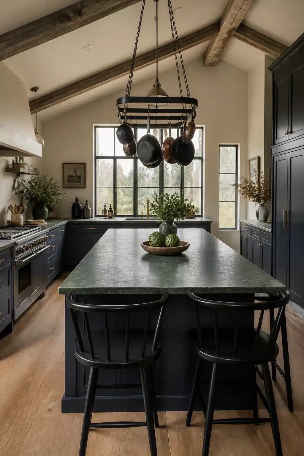 Olive green soapstone kitchen countertop on a navy island with hanging pot rack and exposed wood beams.