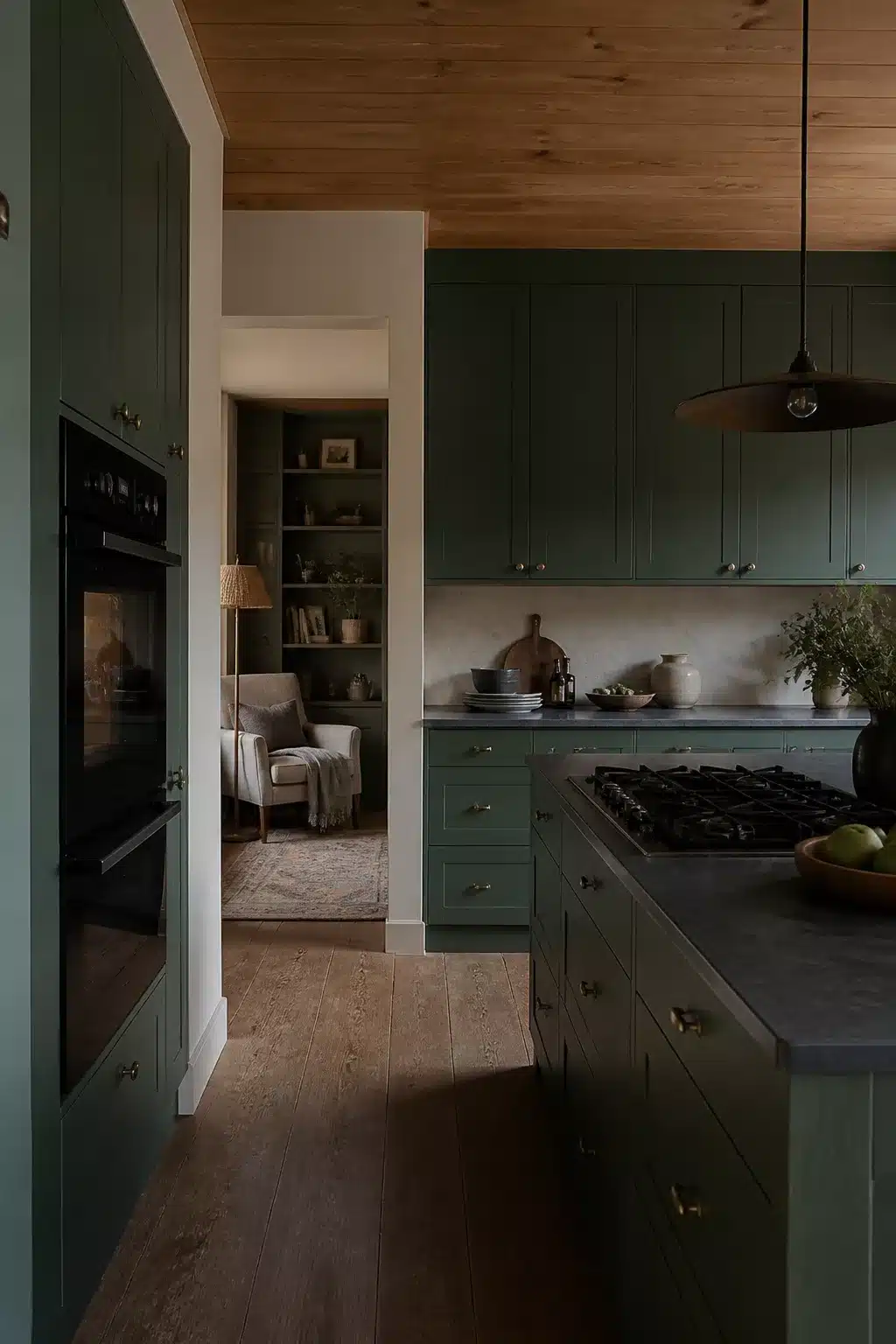 Forest green kitchen with black appliances, wood plank ceiling, dark stone countertops, and brass cabinet hardware