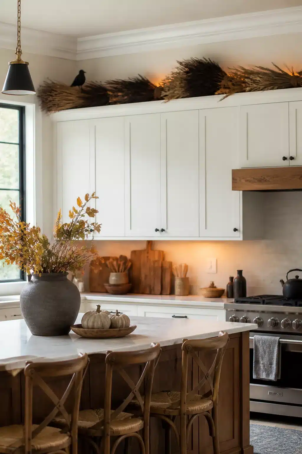 Halloween decor above kitchen cabinets using dried grass bundles and a raven figure on white shaker cabinets