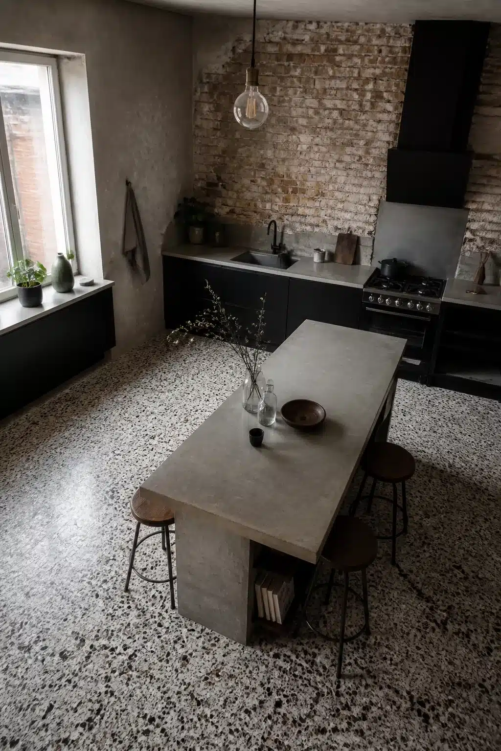 Industrial chic kitchen with terrazzo floor, concrete island bench, exposed brick wall and matte black cabinets