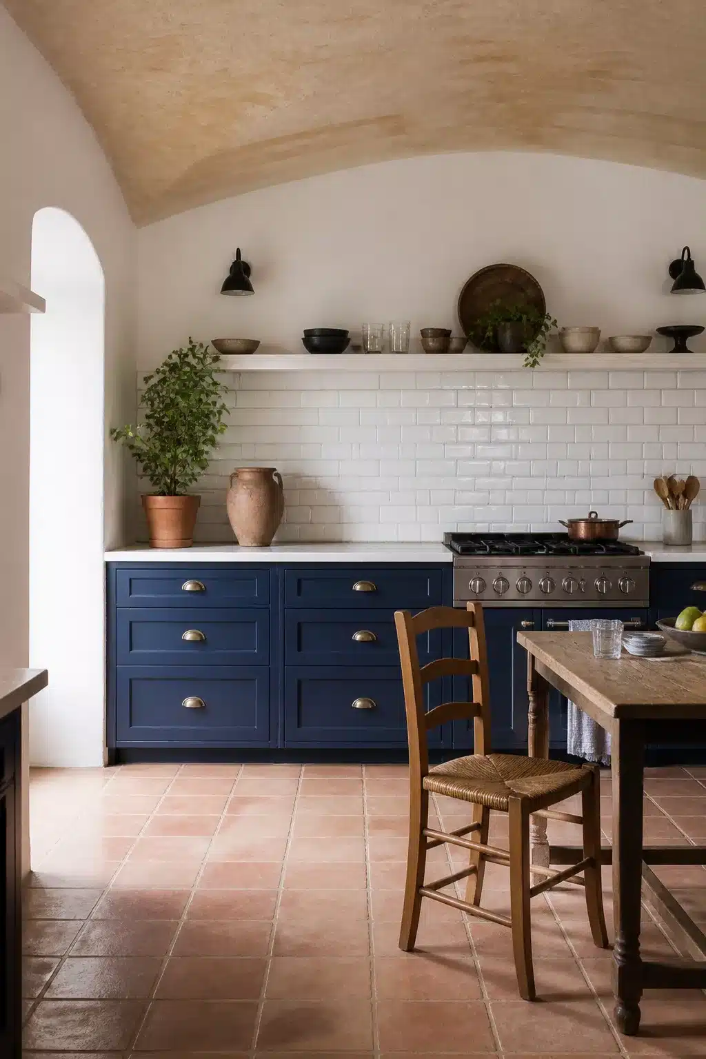 Mediterranean kitchen design with cobalt blue cabinets, aged brass cup pulls, white subway tile backsplash and terracotta floor