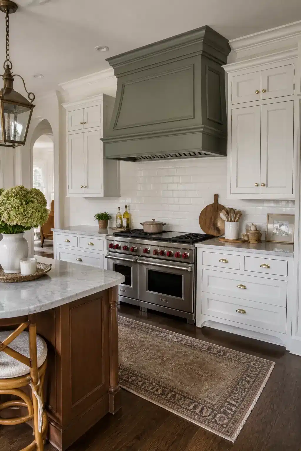 Traditional kitchen remodel idea featuring a painted range hood with crown molding, white cabinets, and brass hardware