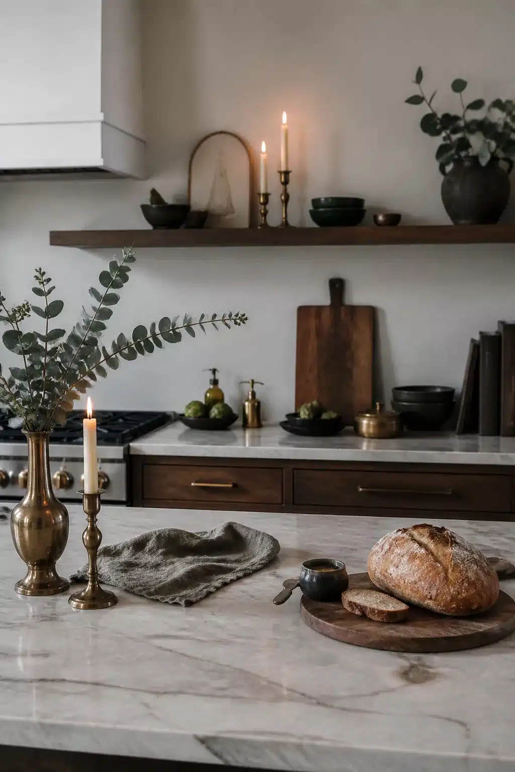 Brass candlesticks and marble island winter kitchen decor ideas with dark wood shelving and eucalyptus stems