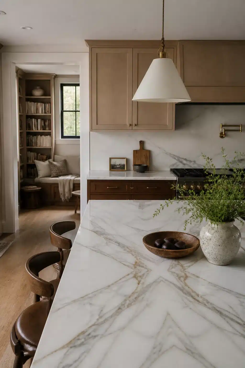 Warm taupe wood kitchen cabinets with bookmatched gold-veined marble countertops and brass accents