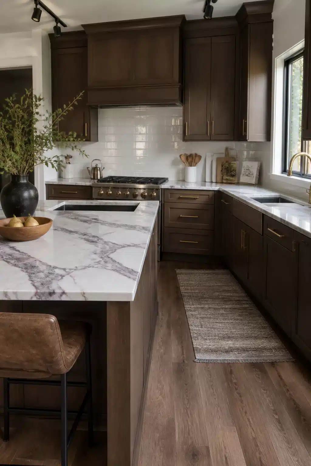 Dark wood kitchen cabinets with white Calacatta Viola marble counters, brass hardware, and white tile backsplash