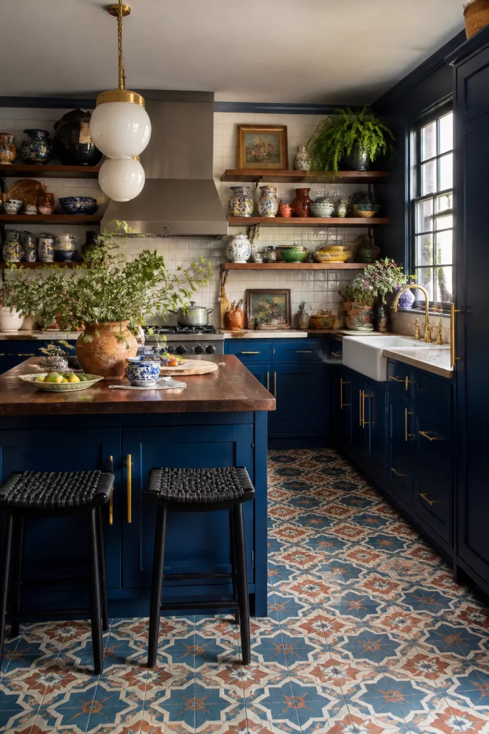 Royal blue kitchen cabinets with gold hardware, encaustic cement tile floor, open shelves, and butcher block island