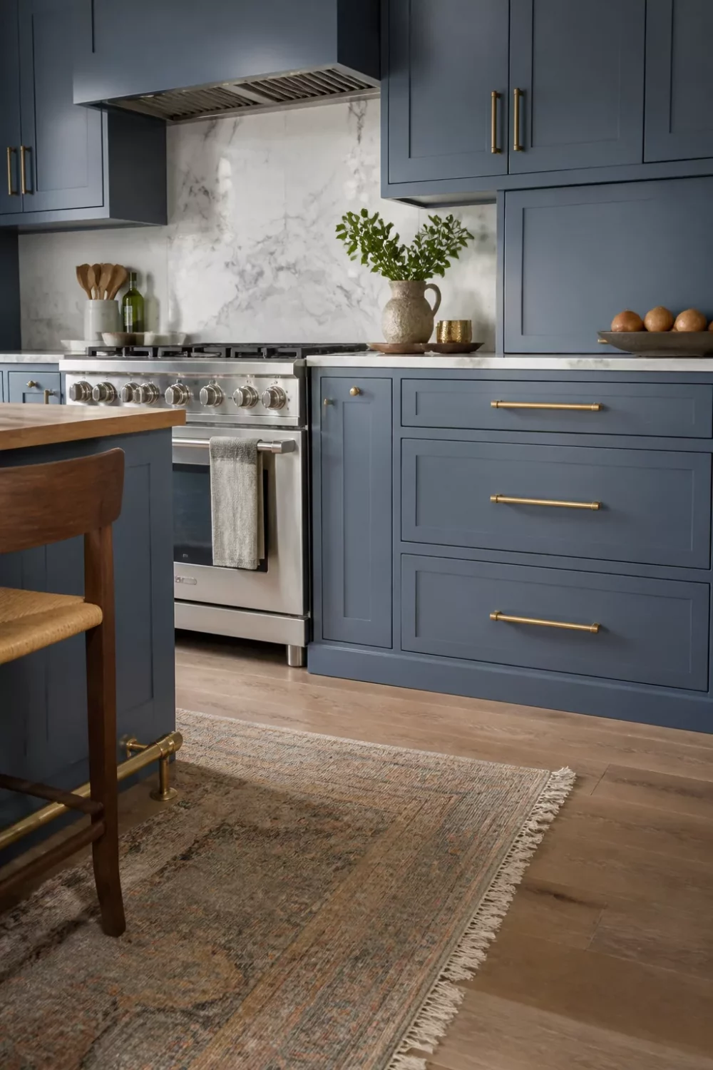 Blue-gray shaker kitchen cabinets with aged gold bar pulls, marble backsplash, and stainless range — blue kitchen cabinets with gold hardware