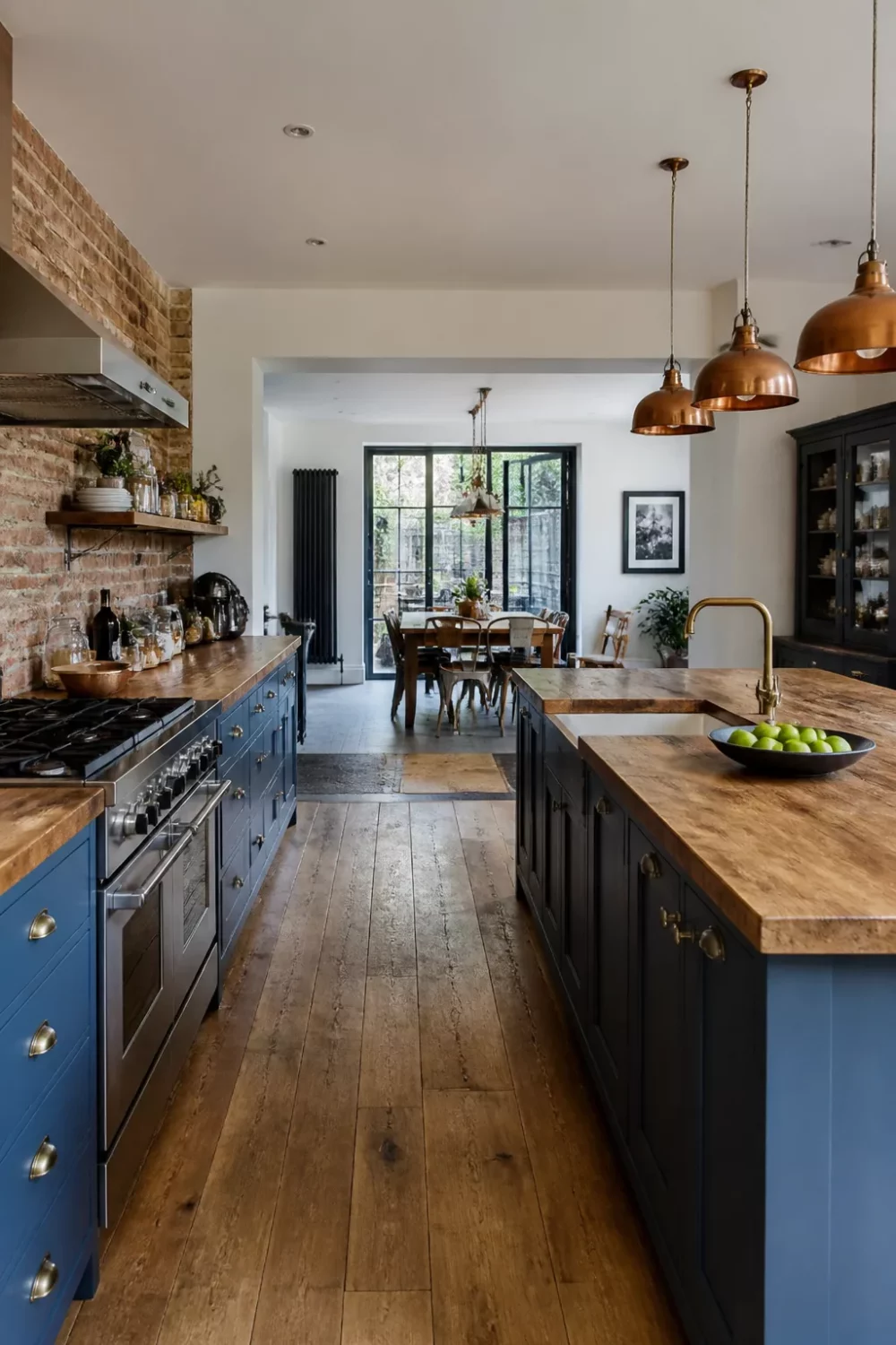 Steel blue kitchen with wood countertops, exposed brick backsplash, copper pendants, and wide plank floors — Blue Kitchens With Wood Countertops