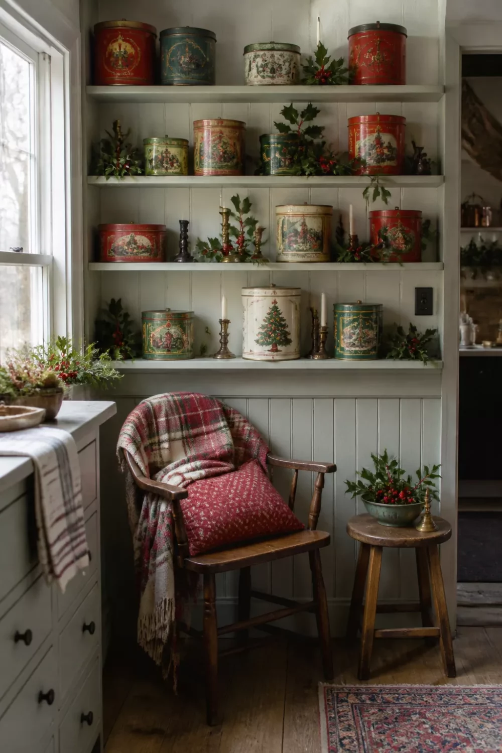 Vintage Christmas cookie tins on white beadboard shelves in a cozy Christmas kitchen ideas corner with holly sprigs