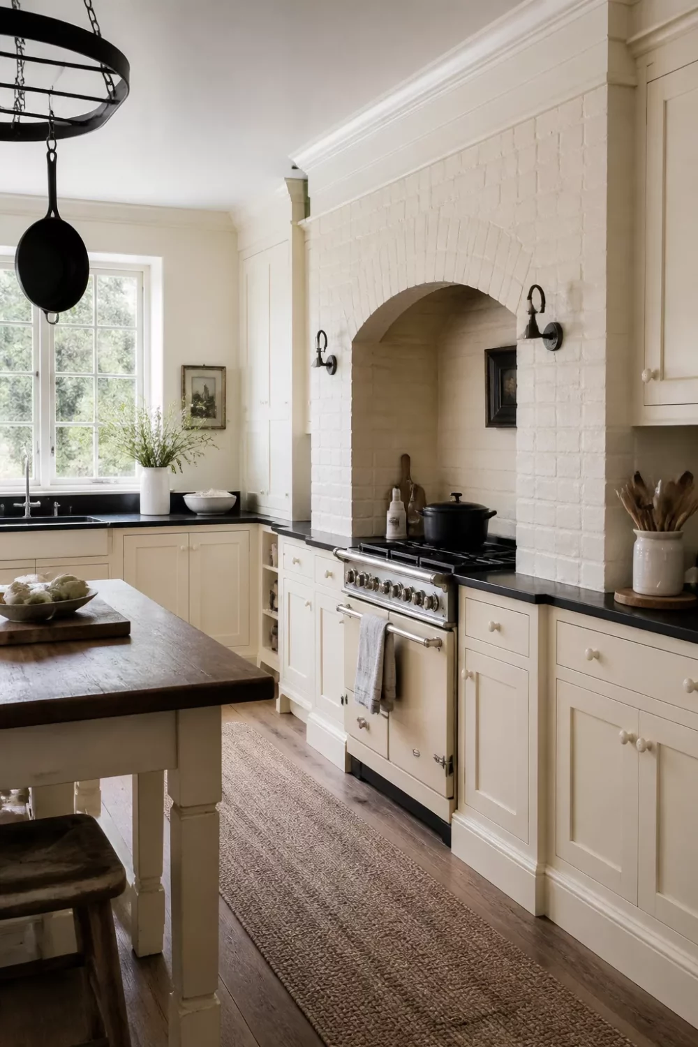 Cream kitchen with black countertops featuring a painted brick arch surround framing a cream range cooker