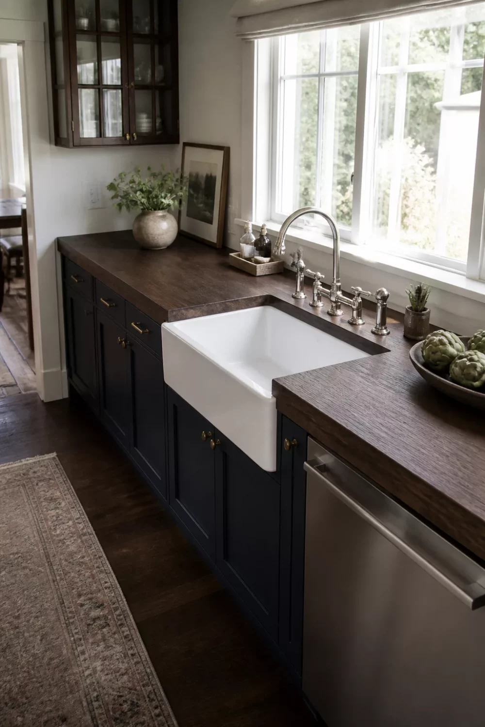 Dark wood kitchen countertops with navy shaker cabinets, farmhouse sink, and brass hardware in a classic kitchen