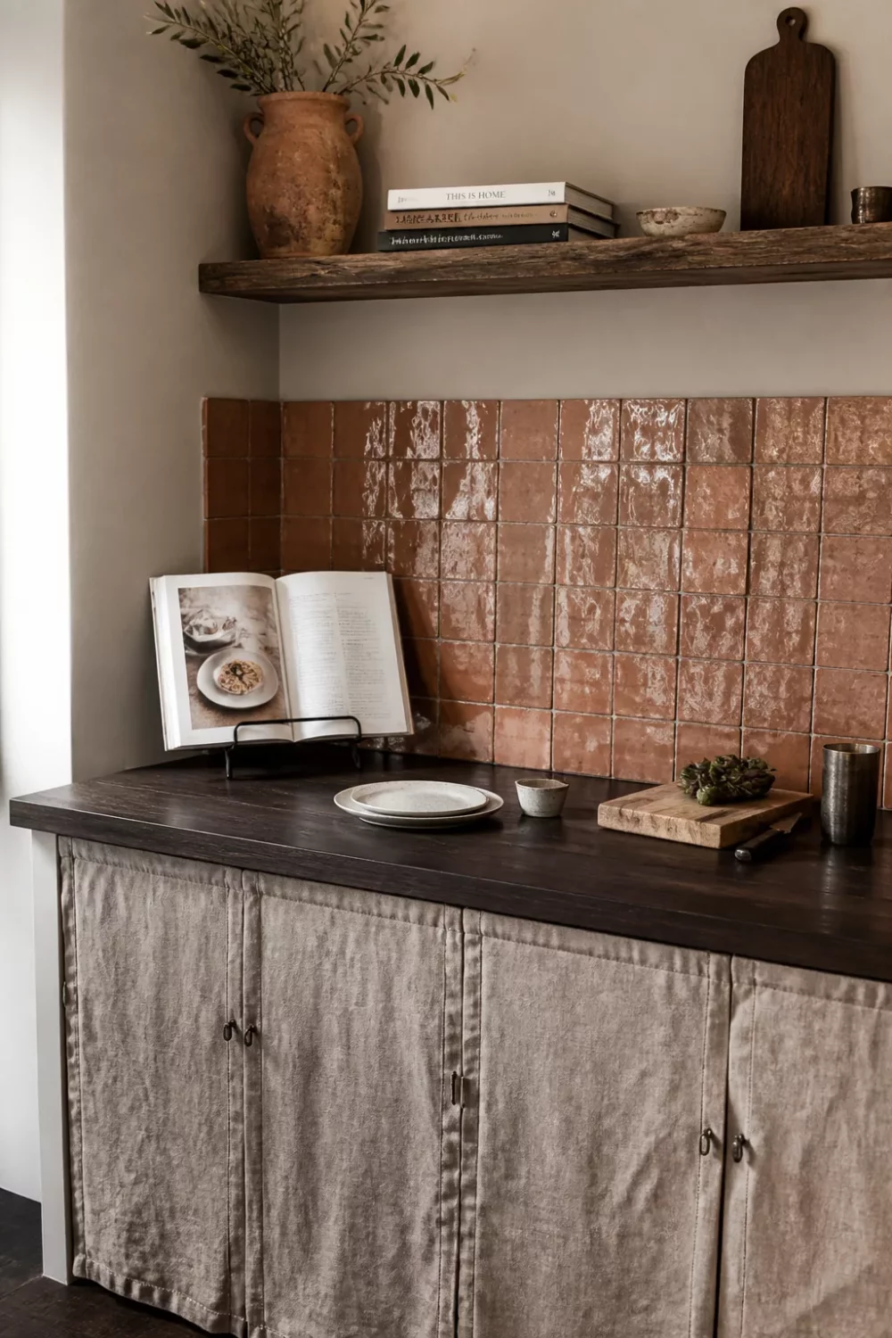 Dark wood kitchen countertop with zellige tile backsplash and linen cabinet curtains in a warm earthy kitchen