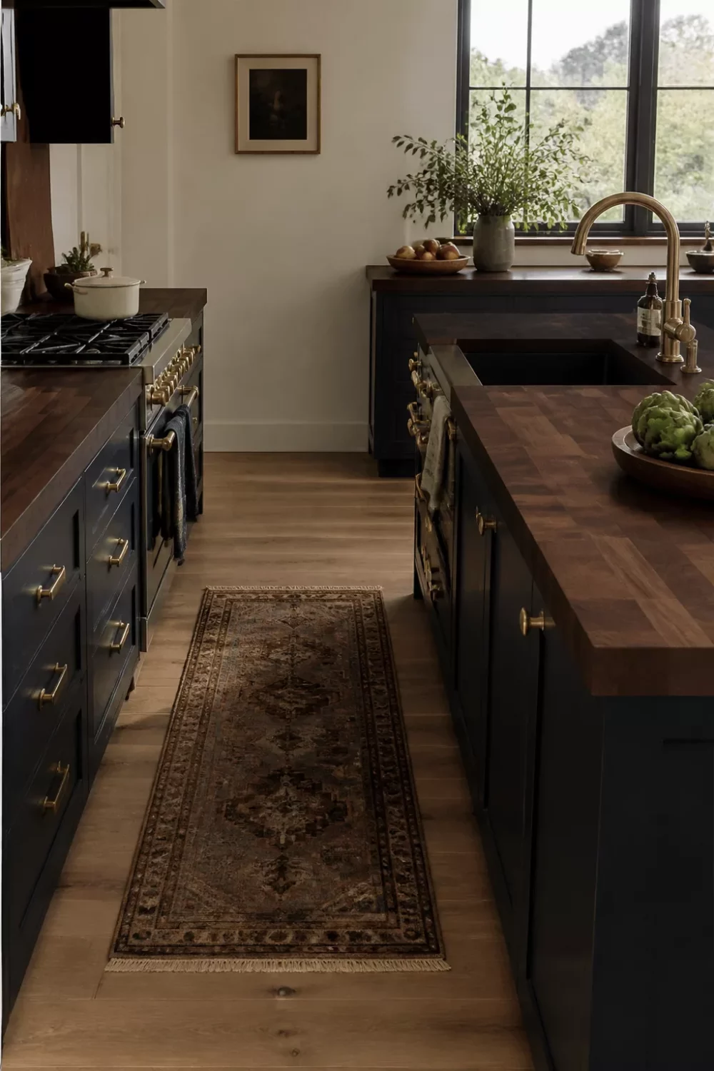 Dark wood kitchen countertops in walnut butcher block with navy cabinets, brass hardware, and a vintage runner rug