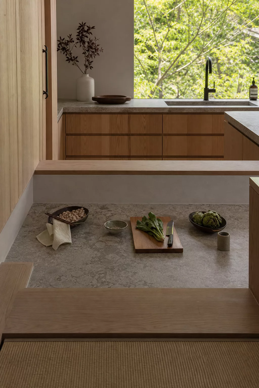 Sunken stone prep counter with wood cabinetry, a Japandi kitchen design idea