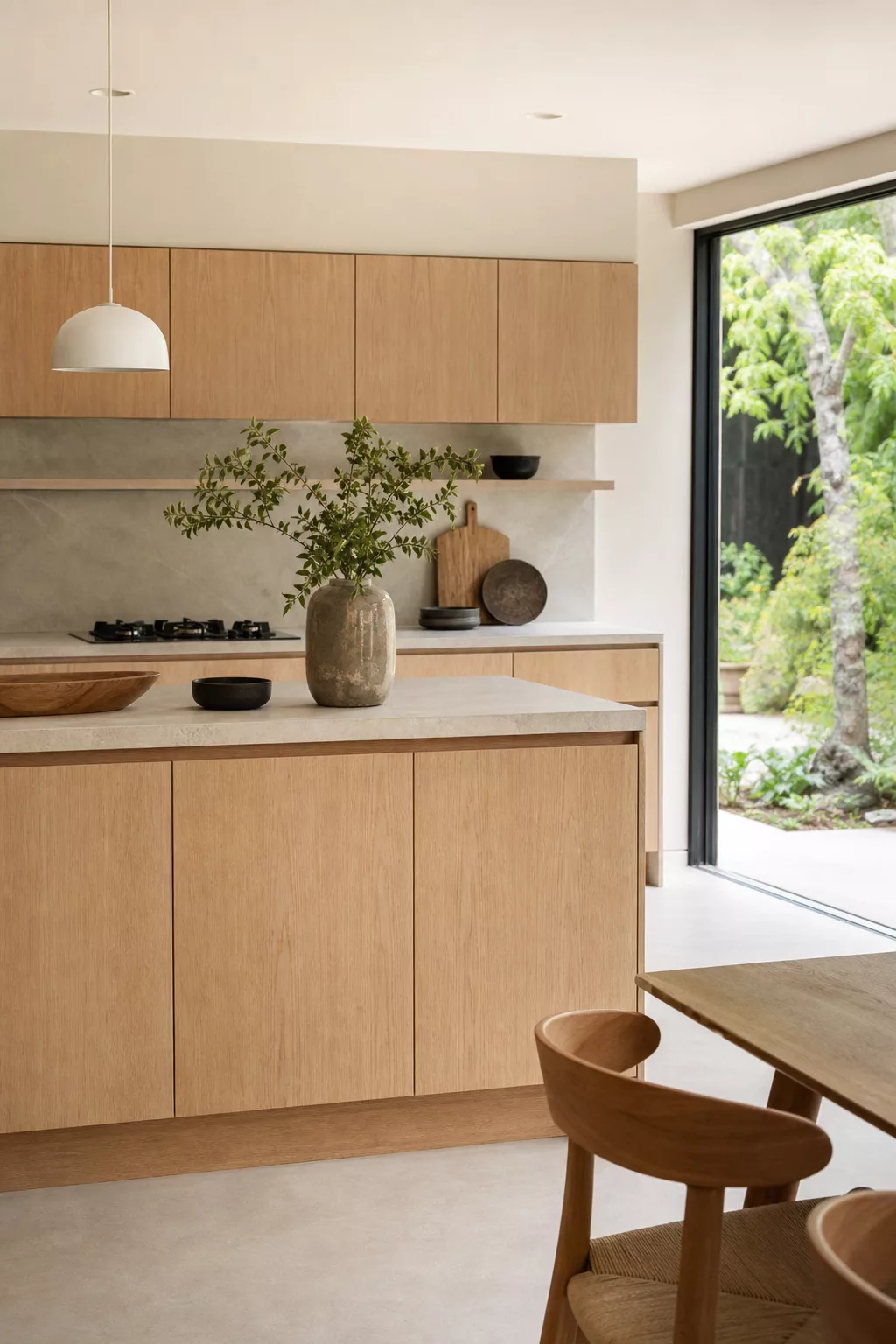 White oak slab cabinets in a minimalist Japandi kitchen design with stone backsplash