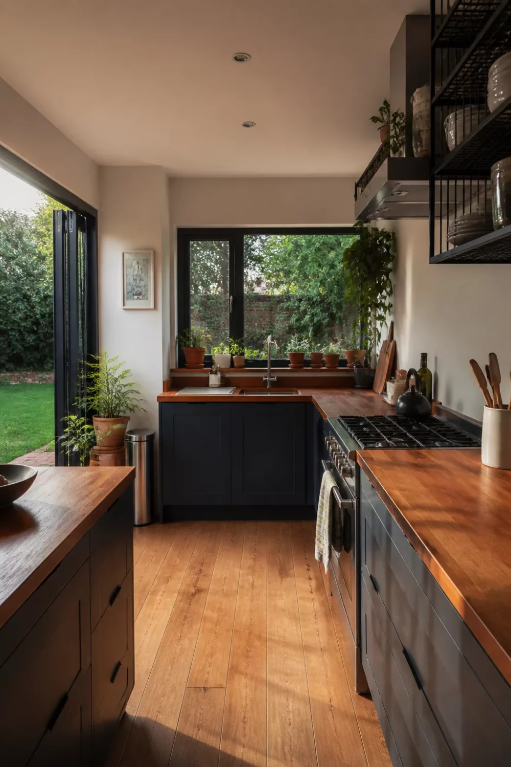 Modern kitchen with wood countertops — dark shaker cabinets, iroko counter, bi-fold doors opening to garden