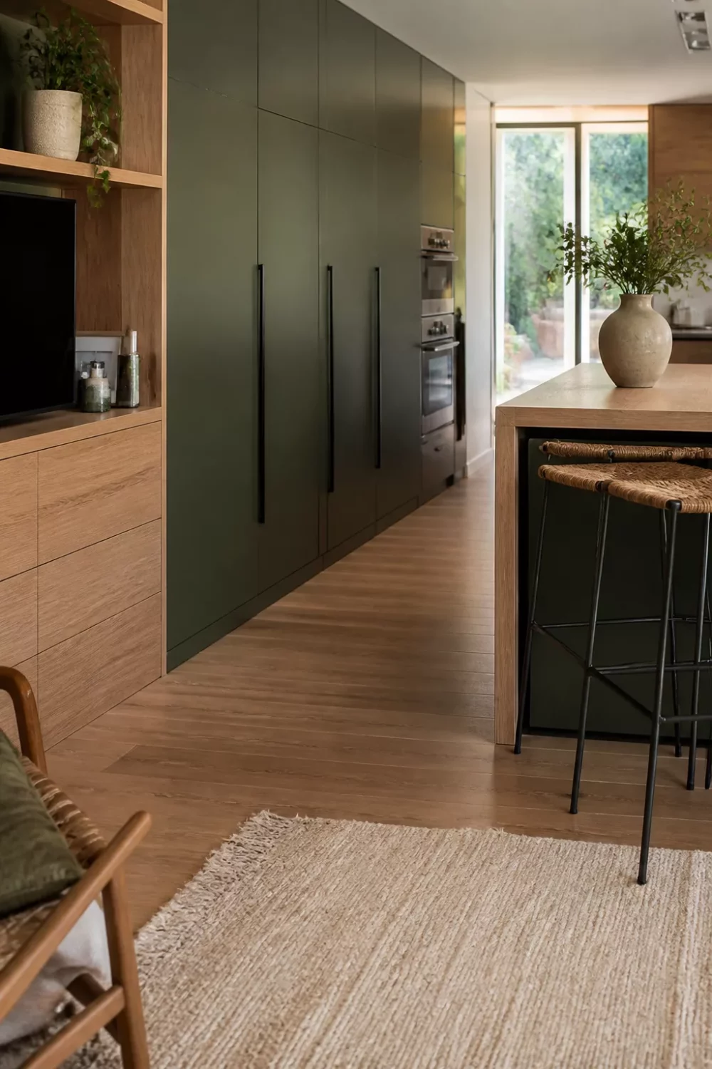 Two tone kitchen cabinets green and wood — cypress green ceiling-height units with warm oak flat-front base cabinets and island